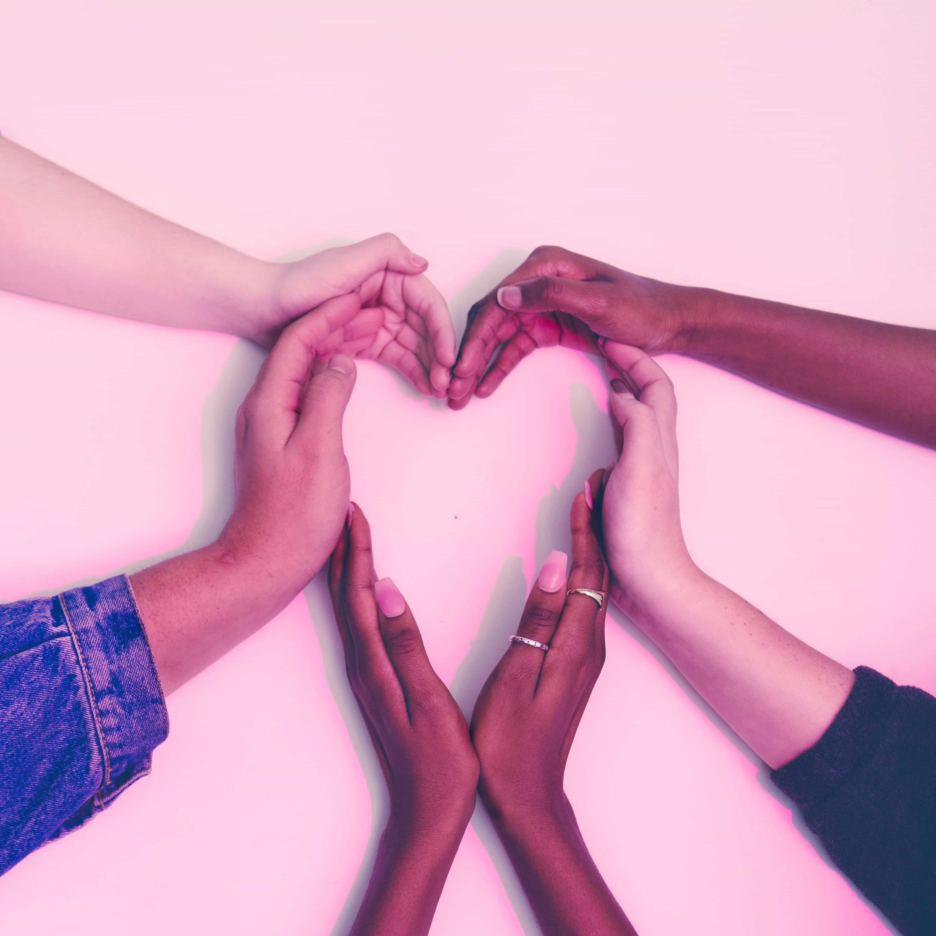 Hands of different skin tones forming a heart shape, representing artistic collaboration and creative connection between The Artist Nest and other creatives.
