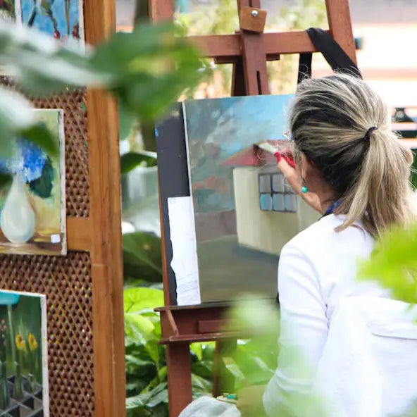Person painting a landscape on an easel outdoors
