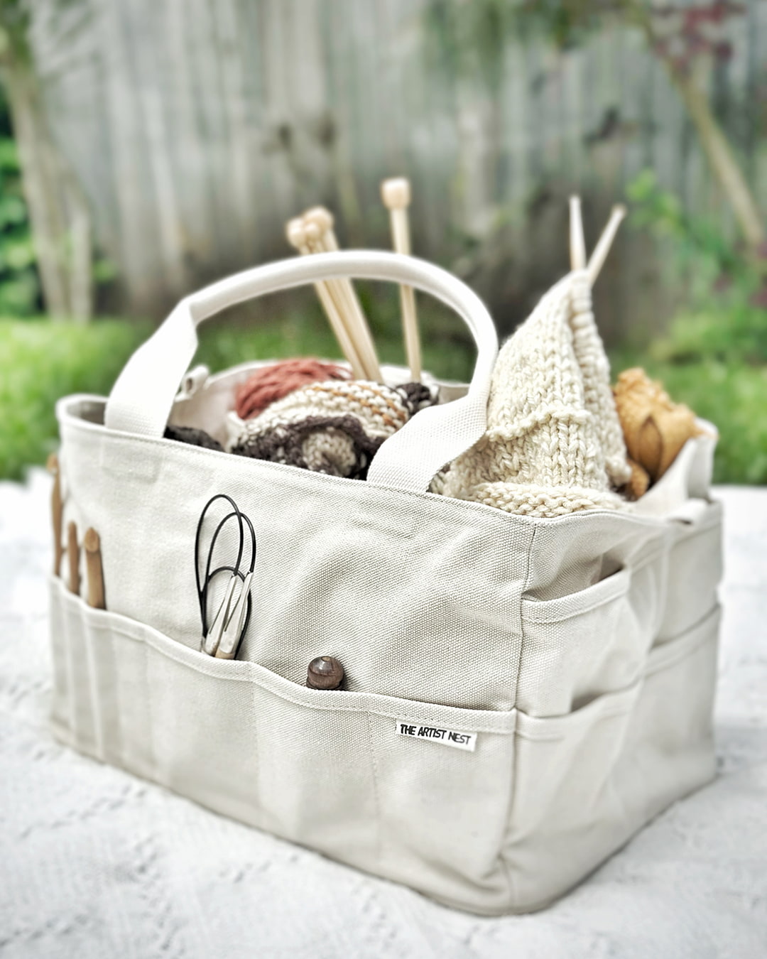 Drift white Artist Bag filled with knitting projects, crochet hooks and yarn tools, a canvas tool organiser ideal for fibre artists, crafters and creative classes in Australia.