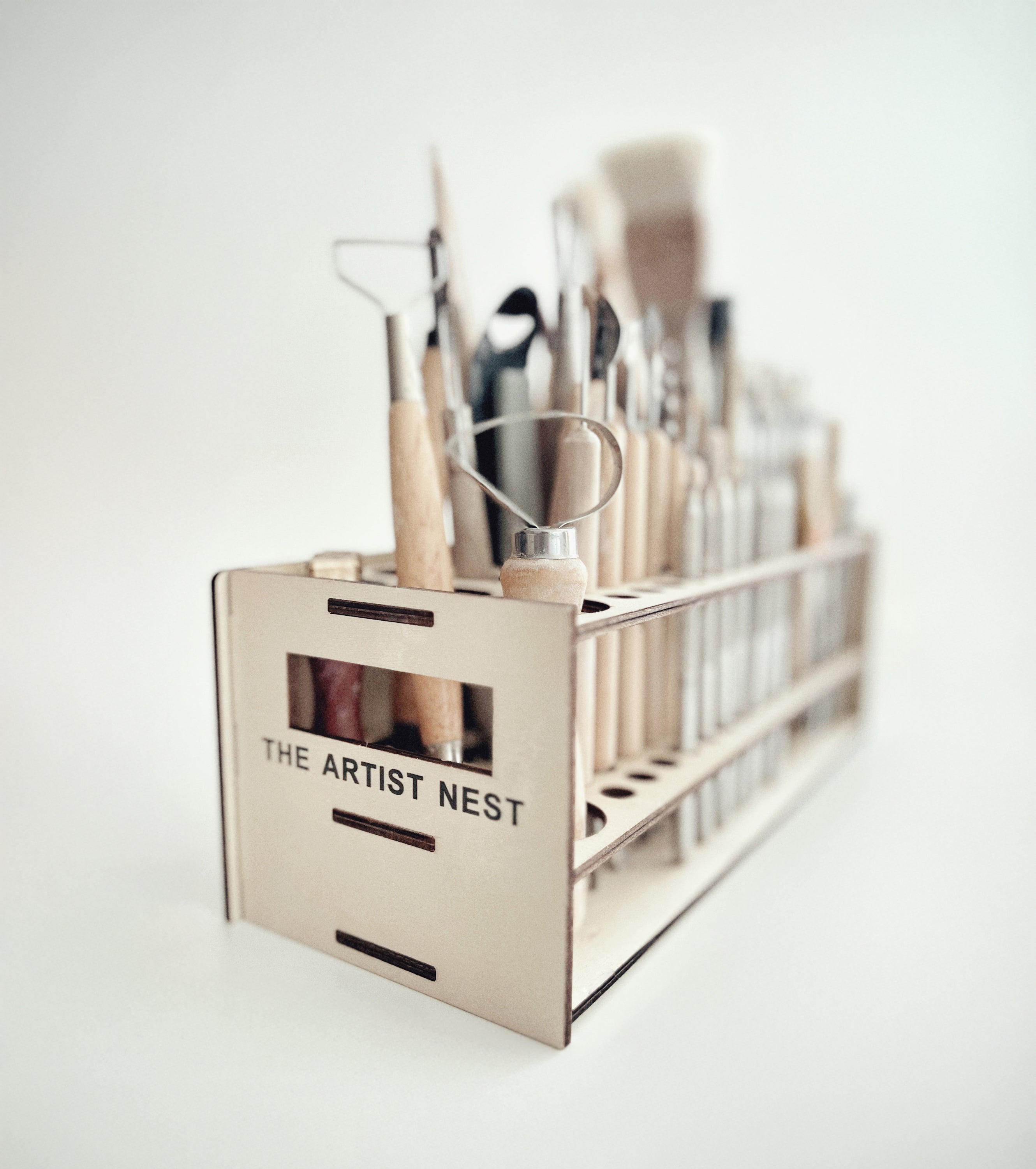 Wooden pottery tool rack made by a potter, with custom-sized holes that fit every pottery tool and keep them easily accessible.